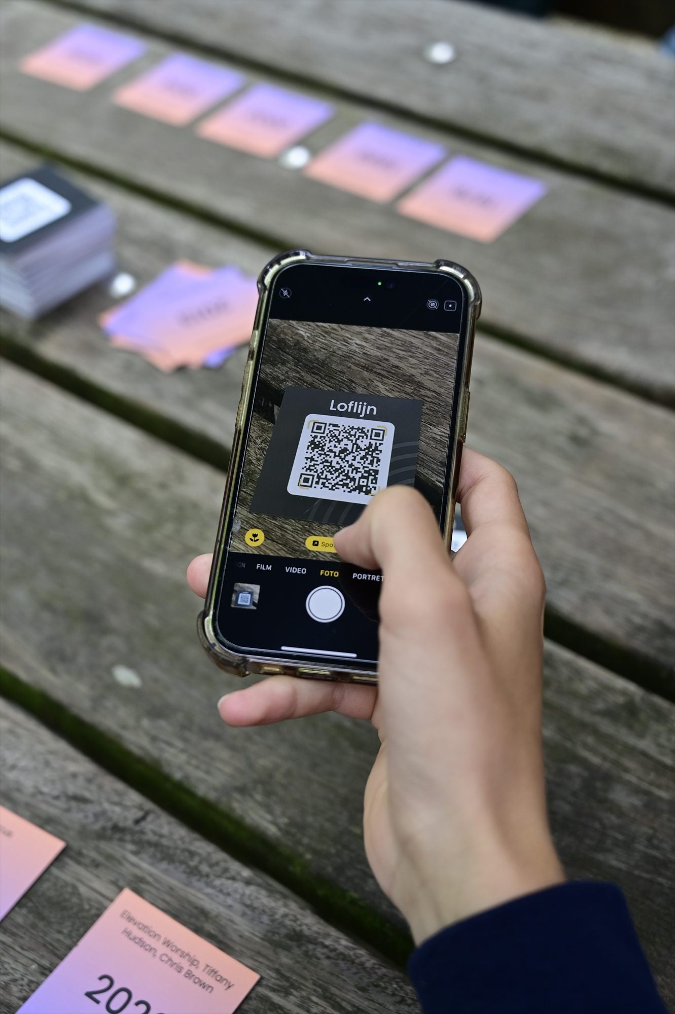 Een telefoon scant de QR-code op een LOFLIJN-kaart aan een houten tafel